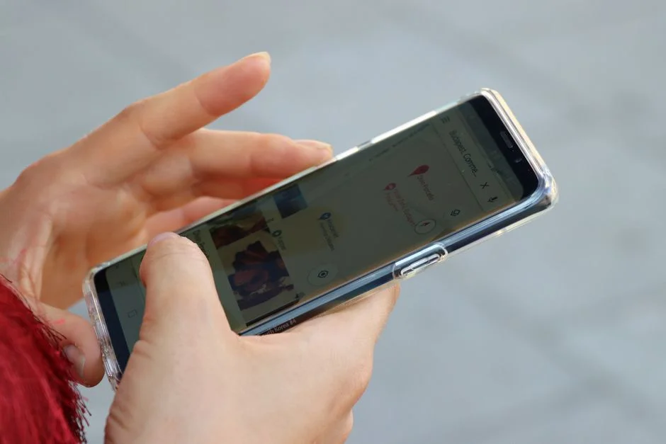 Zwei Hände halten ein Smartphone und rufen darauf eine Kartenansicht auf
