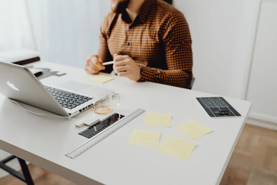 Heller Schreibtisch mit Laptop, Notizzetteln und Stift, an dem die lokale Sichtbarkeit geplant wird