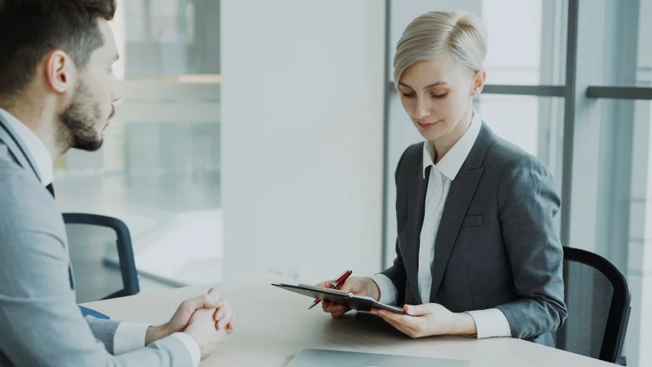 Zwei Personen besprechen in einem hellen Büro Unterlagen im Rahmen eines Beratungsgesprächs