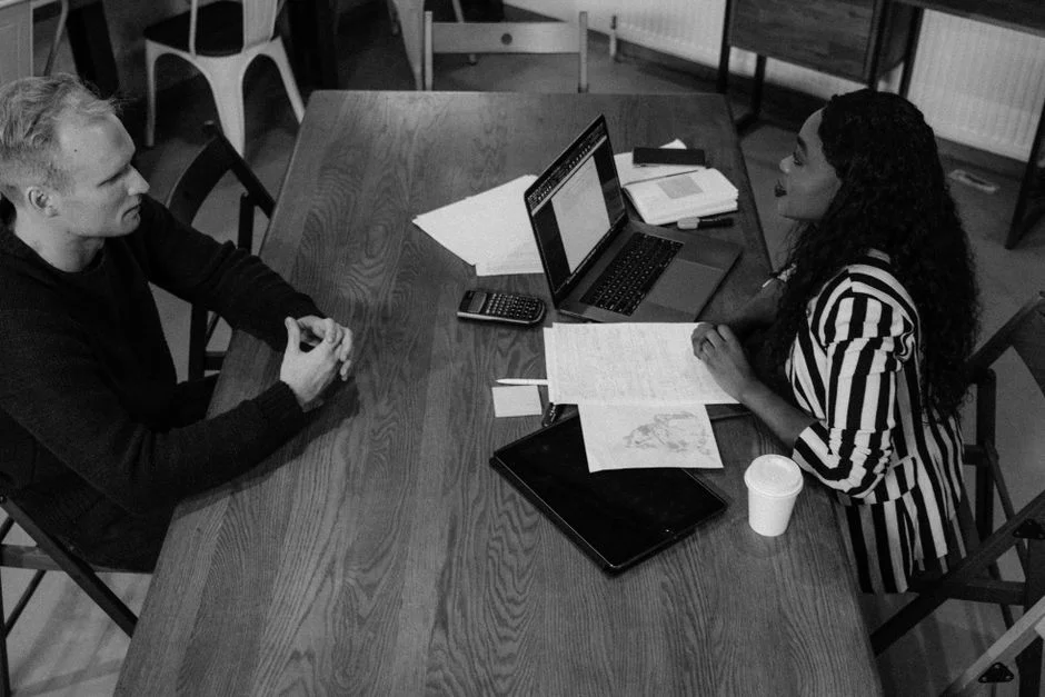 Kleines Team bespricht Website-Projekt mit Unterlagen und Laptop